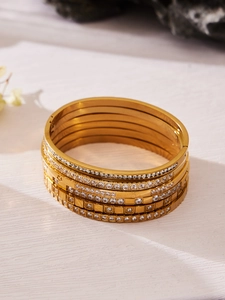Dettaglio del set di bracciali in acciaio dorato con design minimalisti e pavé di zirconi