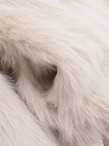 Vue macro de la texture de fausse fourrure crème et des fibres soyeuses du manteau