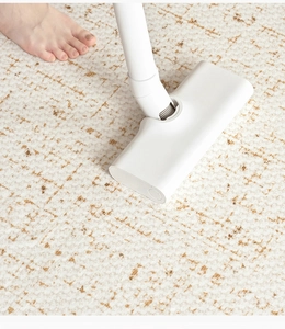 Close-up of a white carpet cleaner brush head on a patterned rug for easy maintenance