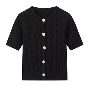 Detail of black cable knit cardigan showing silver relief buttons and ribbed neckline texture