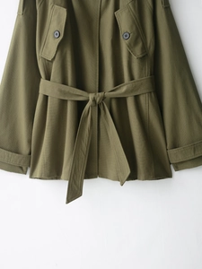 Detail of army green cotton trench coat showing waist belt tie and black buttons