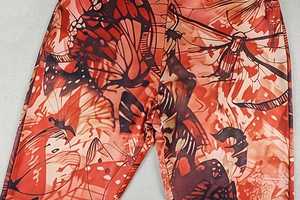 Detail of retro butterfly print on orange and brown elastic high-waisted trousers