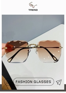 Close-up of frameless sunglasses featuring wavy edge gradient brown lenses and gold hardware