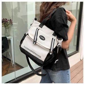 Detail of canvas tote bag showing black and white contrast panels and fashion logo tag