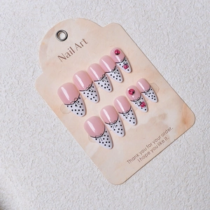 Detail of French pink press-on nails with white polka dots and cute ladybug accents