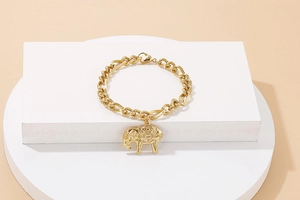 Detail of a chunky gold chain bracelet featuring an ornate elephant pendant on display