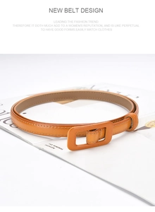 Close-up of caramel leather belt with a square leather-wrapped buckle on a magazine