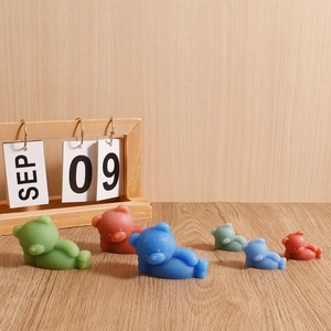 Detailed view of matte silicone bear candle molds in various sizes and colors on wood
