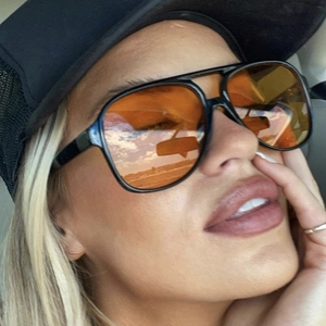 Close-up of retro oversized pilot sunglasses with orange lenses on a model in a car