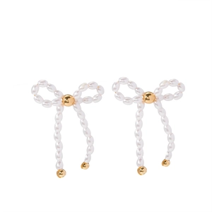 Detailed view of French bow earrings with white pearls and golden metallic accents