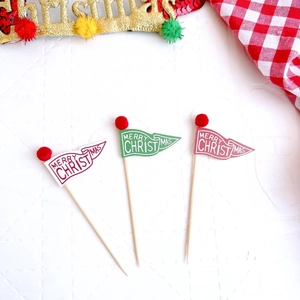 Détail de trois décorations de gâteau Joyeux Noël avec drapeaux en papier rouge et vert et bois