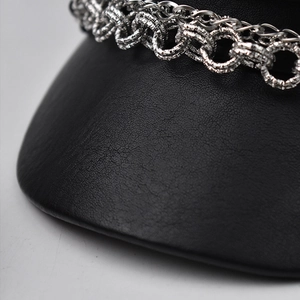 Close-up of silver metal chain with diamond-cut texture on black textured leather