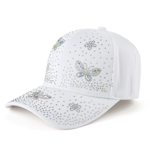 Vue détaillée des motifs de papillon en strass étincelants sur une casquette en coton blanc