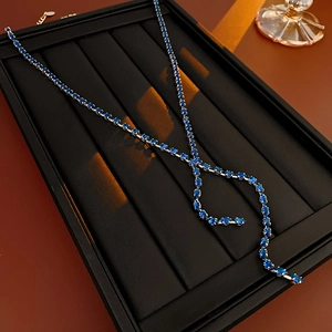 Detail of silver tassel necklace with blue marquise crystals on black leather display tray