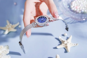 Close-up of luxury women's watch with blue pearl dial, rhinestone bezel and silver mesh strap