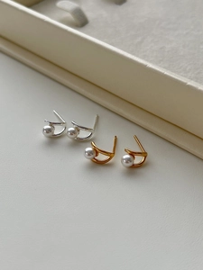 Macro shot of minimalist sterling silver pearl earrings in gold and silver finish