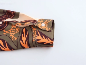 Detailed close-up of shirt cuff with retro floral pattern and white button closure