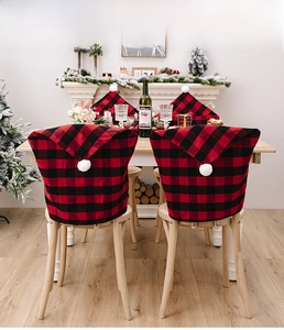 Close-up of red and black buffalo plaid Christmas chair covers with white pom-poms