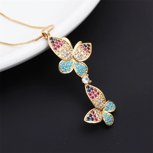 Macro detail of gold butterfly pendant with colorful zircons on a white ceramic tray