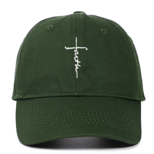 Close-up of white faith cross embroidery on a dark green cotton baseball cap crown