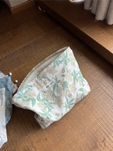 Detail der floralen Canvas-Kulturtasche mit Reißverschluss auf dunklem Holzboden