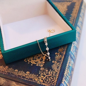 Elegante collar de plata bañada en oro de 14k con cinco zirconias en un libro antiguo