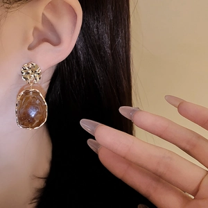 Macro view of vintage irregular amber resin earrings with gold hammered metal details