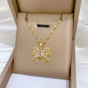 Macro view of gold bow pendant necklace with zircon crystals on champagne satin base