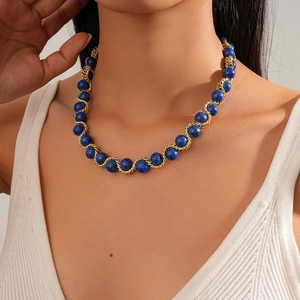 Dettaglio di una collana a catena intrecciata dorata vintage con perle di pietra blu