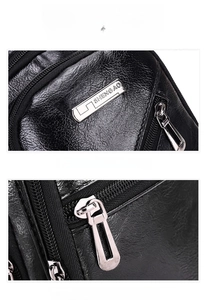 Detail van de leren borsttas met lycheetextuur, zilveren logo en luxe ritssluiting