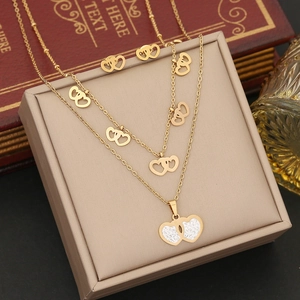Détail d'un ensemble de collier cœur double couche et boucles d'oreilles dorés sur boîte
