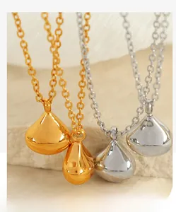 Macro shot of polished gold and silver water drop pendants on stone surface