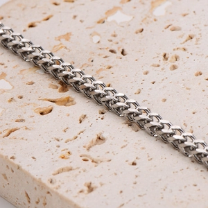 Polished silver stainless steel hip-hop style curb chain bracelet on a warm stone background