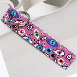 Detail of purple faux leather keychain featuring artistic cartoon eyes and metal ring
