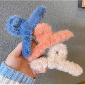 Three large plush faux fur shark hair clips in blue, orange pink, and beige colors