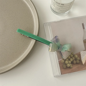 Detail of green acetate bow hair clip with France Handmade lettering on a white background