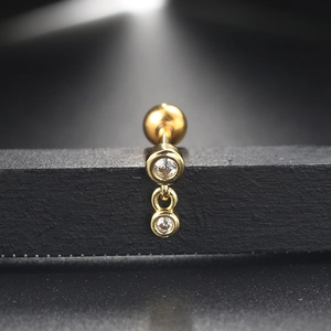 Macro detail of golden vertical double-zircon stud earring with screw back on black stand