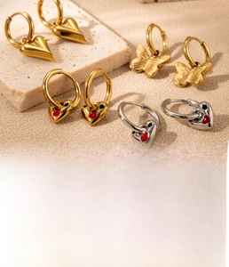 Macro detail of gold titanium steel heart and butterfly earrings with zircon stones