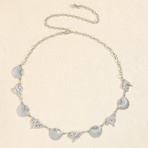 Detail of silver beach waist chain with starfish and seashell charms on textured background