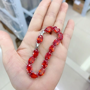 Elegant silver tennis bracelet with oval red AAA garnets held by hand in clear detail