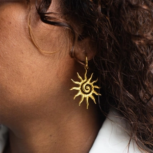 Vintage golden sunburst earrings with spiral center and textured matte finish on model