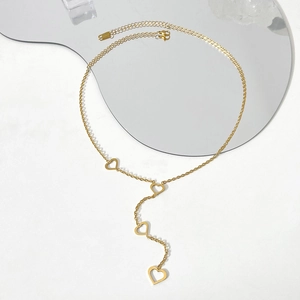 Close-up of golden stainless steel Y-necklace with hollow heart pendants on white background