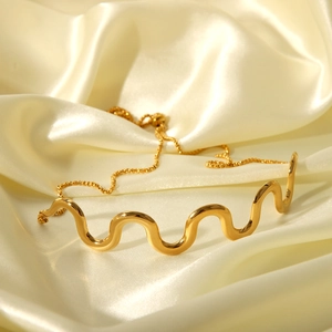 Detailed view of gold wave bracelet on silk fabric with adjustable chain toggle