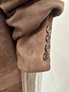 Detail of the brown faux suede jacket sleeve featuring four tortoiseshell textured buttons