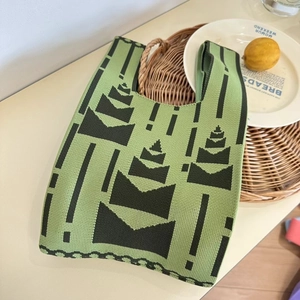 Detailed close-up of a green and black knitted tote bag with geometric tree patterns