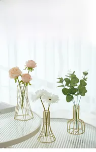 Detail of geometric gold metal frame vases with glass inserts and floral arrangements