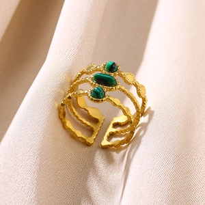 Detail shot of multi-layer gold ring with green malachite stones on beige fabric