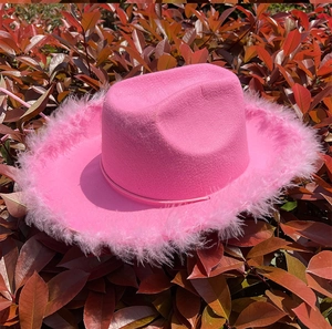 Primer plano de sombrero vaquero rosa con ribete de plumas y textura aterciopelada