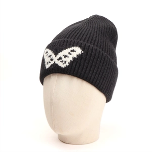 Detail view of a black ribbed knit beanie featuring a white butterfly jacquard pattern