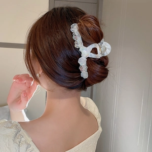 Gros plan sur une pince à cheveux élégante en nacre irisée portée sur un chignon bas